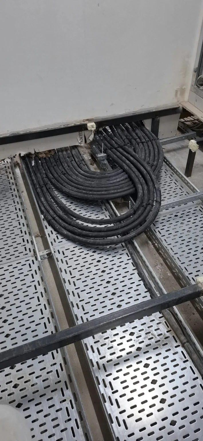 Elektrik panosu altında metal kablo tavasına yerleştirilmiş güç kabloları